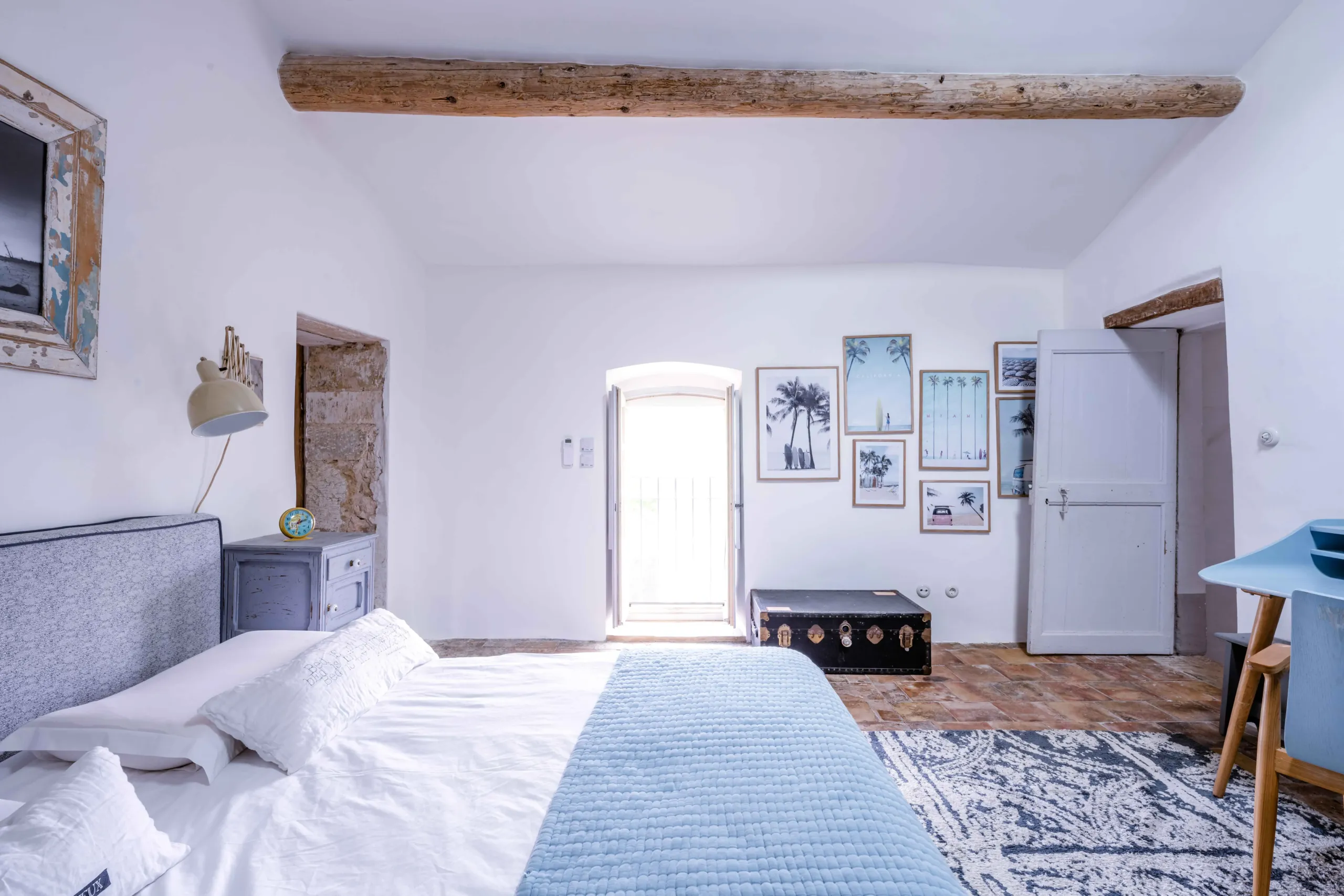 Chambre lumineuse avec décoration murale et lit bleu.