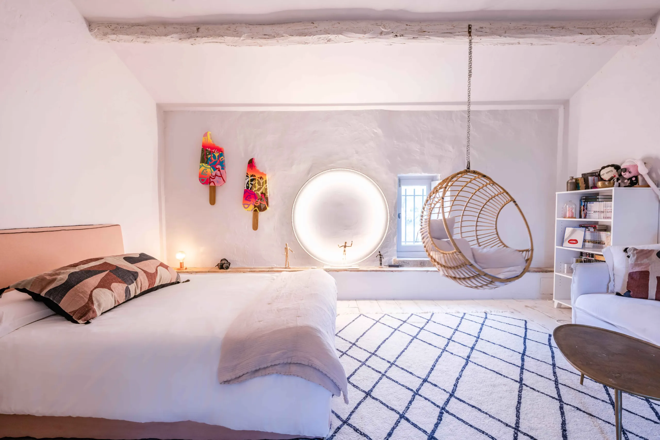 Chambre lumineuse avec fauteuil suspendu et décoration artistique.