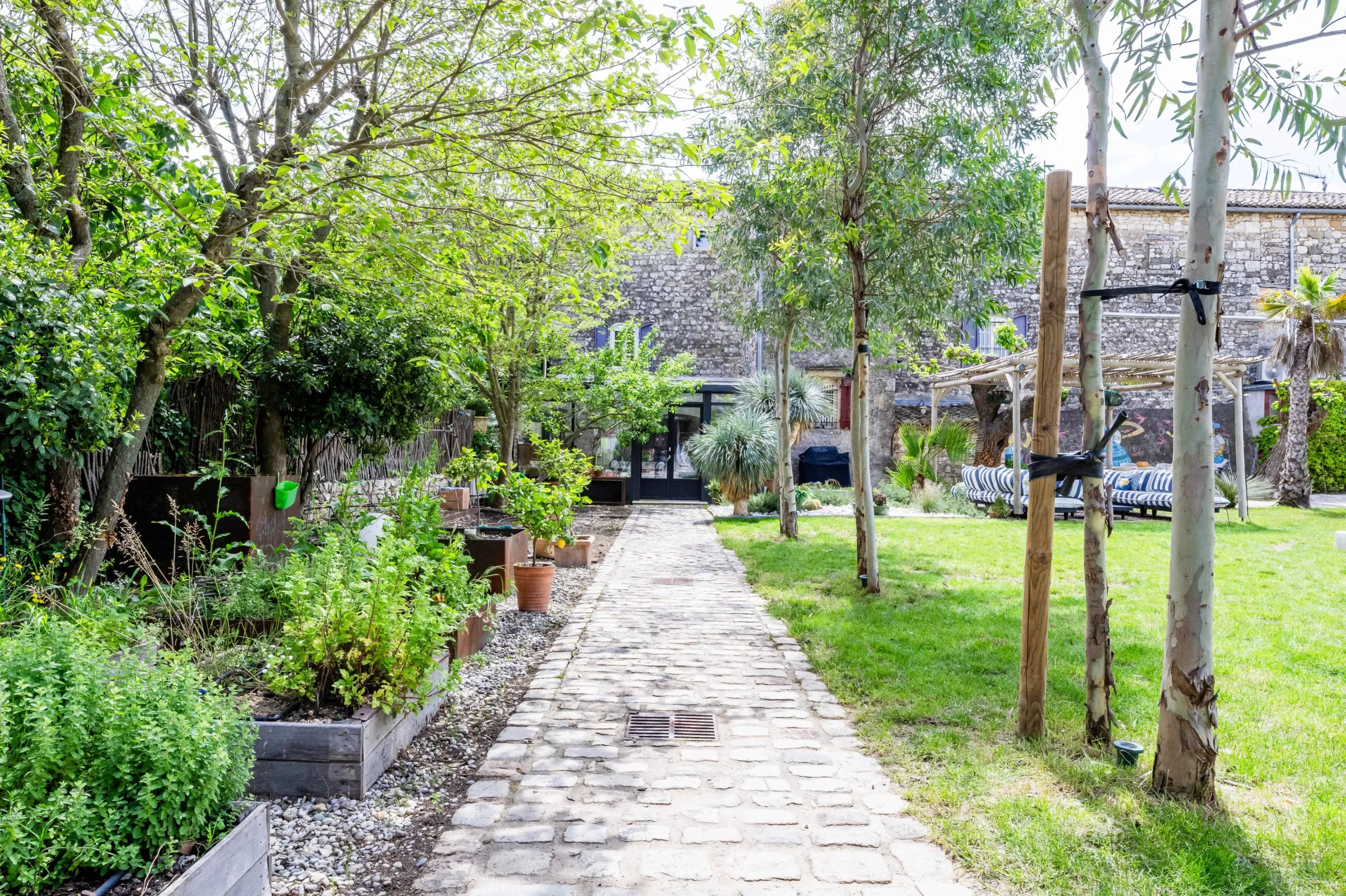 Jardin avec allée pavée et plantes verdoyantes.